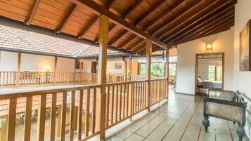 Un espacio al aire libre techado con barandillas de madera, un banco y piso de baldosas.