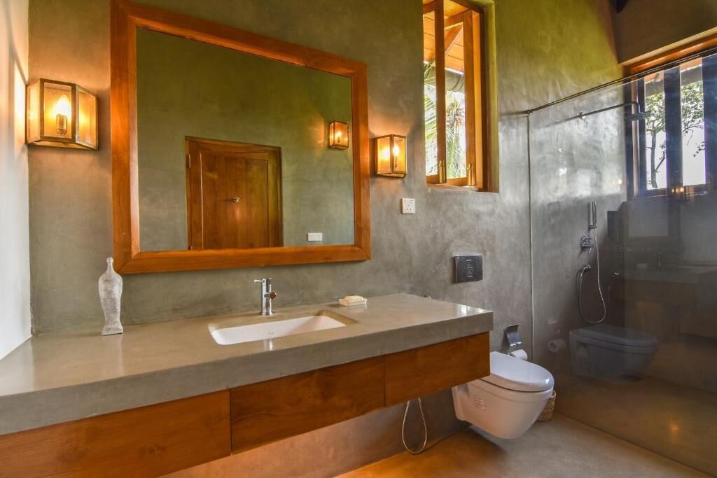 A bathroom with a large mirror, a sink, a toilet, and a shower.