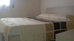 Ein Bett mit einem gemusterten Überwurf, einem schlichten Kopfteil und einem Nachttisch.
