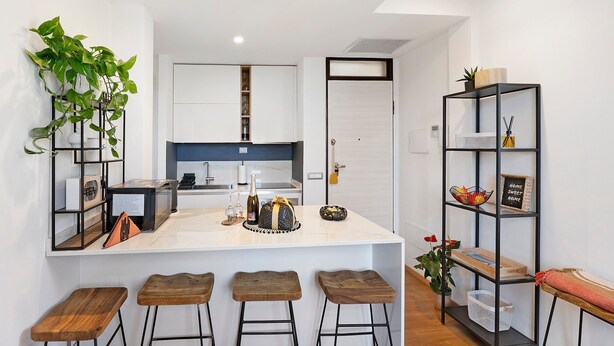 A modern kitchen with a central island, bar stools, a bookshelf, and a potted plant. - Apartment 'Citrus Garden' with Mountain View, Wi-Fi and Air Conditioning (Cisano sul Neva)