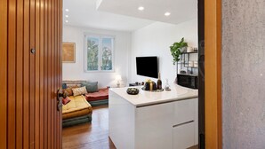 A modern kitchen with a flat-screen TV, a dining area with a table and chairs, and a cozy seating area with a sofa and cushions. - Apartment 'Citrus Garden' with Mountain View, Wi-Fi and Air Conditioning (Cisano sul Neva)
