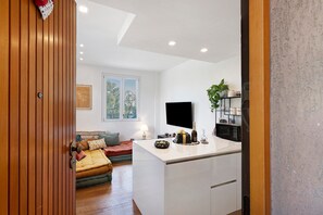 A modern kitchen with a flat-screen TV, a dining area with a table and chairs, and a cozy seating area with a sofa and cushions. - Apartment 'Citrus Garden' with Mountain View, Wi-Fi and Air Conditioning (Cisano sul Neva)