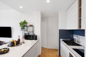 A modern kitchen with white cabinets, a built-in microwave, a sink, and a small plant. - Apartment 'Citrus Garden' with Mountain View, Wi-Fi and Air Conditioning (Cisano sul Neva)