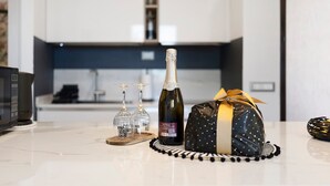 A kitchen counter with a bottle of champagne, a wrapped gift, and two wine glasses. - Apartment 'Citrus Garden' with Mountain View, Wi-Fi and Air Conditioning (Cisano sul Neva)
