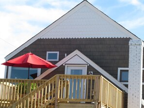 A house with a wooden deck, a red umbrella, and a white brick chimney. - 900. B Seaside 2 Br Cottage with Bay Views, Veranda, High Ceilings, Hot Tub, Private Beach, Beachfront Grilling, & Kayaks (Norfolk)