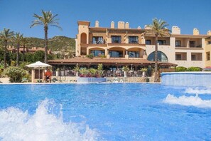A hotel with a pool area, palm trees, and a mountainous backdrop. - Holiday Village Bonavista de Bonmont (Mont-roig del Camp)