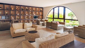 A spacious living area with wicker furniture, a large arched window, and a wall of shelves with decorative items. - Holiday Village Bonavista de Bonmont (Mont-roig del Camp)