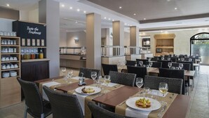A restaurant with multiple dining tables, some with wine glasses and plates, and a bar area with shelves of bottles. - Holiday Village Bonavista de Bonmont (Mont-roig del Camp)