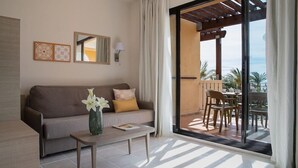 A modern living room with a sofa, coffee table, and a view of an outdoor patio with chairs and a table. - Holiday Village Bonavista de Bonmont (Mont-roig del Camp)