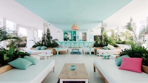 A spacious indoor area with white sofas, a central table, and a teal-colored counter. - Beach Star Ibiza Hotel (Sant Josep de sa Talaia)