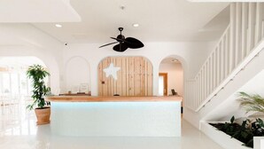 A reception area with a wooden star decoration, a ceiling fan, and a staircase with white railings. - Beach Star Ibiza Hotel (Sant Josep de sa Talaia)
