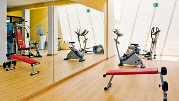 A gym with exercise equipment, a mirror, and a wooden floor.