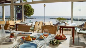 Un área de comedor al aire libre con mesas dispuestas para comidas, con vista a una masa de agua.