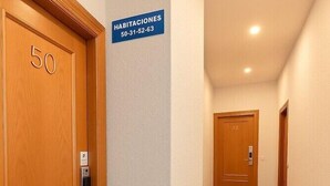 A hallway with wooden doors, a sign indicating room numbers, and a light-colored wall.