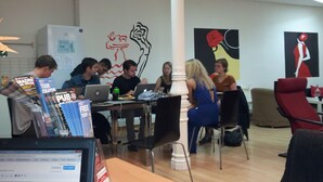 A modern office space with a group of people working at desks, a large white column, and abstract art on the walls.