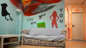 A room with a sofa, a table, and a wall with a mural.