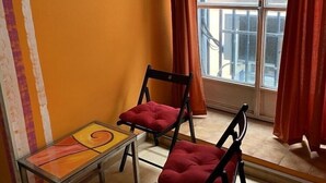 A room with two chairs, a small table, and a large window with curtains.