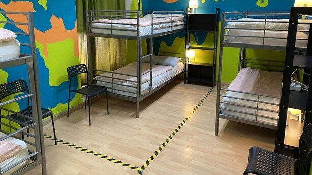 A bunk bed room with a world map mural, a chair, and a bed with a lamp.