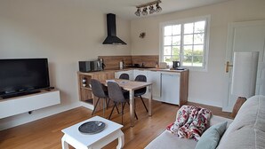 Un espace de vie compact comprenant un téléviseur, un coin cuisine, un espace repas et un canapé.