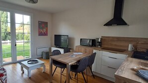 Une cuisine moderne avec un coin repas, un téléviseur et une grande fenêtre.