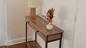 Une console en bois, ornée d’une lampe et d’un vase décoratif, est placée contre un mur où sont accrochés des miroirs ronds.