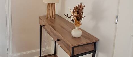 A wooden console table with a lamp and decorative vase against a wall with circular mirrors.