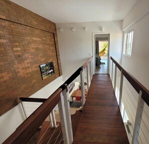 Una scala in legno con ringhiere bianche che conduce a un balcone con vista sull'esterno.