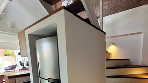 Eine moderne Küche mit einem Edelstahl-Kühlschrank, einer Holztreppe und einer kleinen Essecke.
