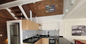Una cucina moderna con un frigorifero in acciaio inossidabile, un piano di lavoro nero e una parete di fondo rivestita di piastrelle.
