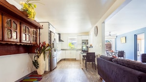 A modern kitchen with white cabinets, a dining area with a dark sofa, and a colorful rug. - Very nice spacious apartment with Jacuzzi - Le Canopé (Le Gosier)
