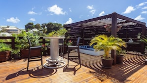 A wooden deck with a pergola, potted plants, and outdoor furniture. - Very nice spacious apartment with Jacuzzi - Le Canopé (Le Gosier)