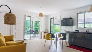 A modern kitchen with a dining area, large windows, and a yellow sofa. - Modern villa with pool in a natural setting (Les Abymes)