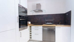 Eine moderne Küche mit weißen Schränken, einem Edelstahl-Geschirrspüler, einer Glaskochplatte und einer Holz Arbeitsplatte.