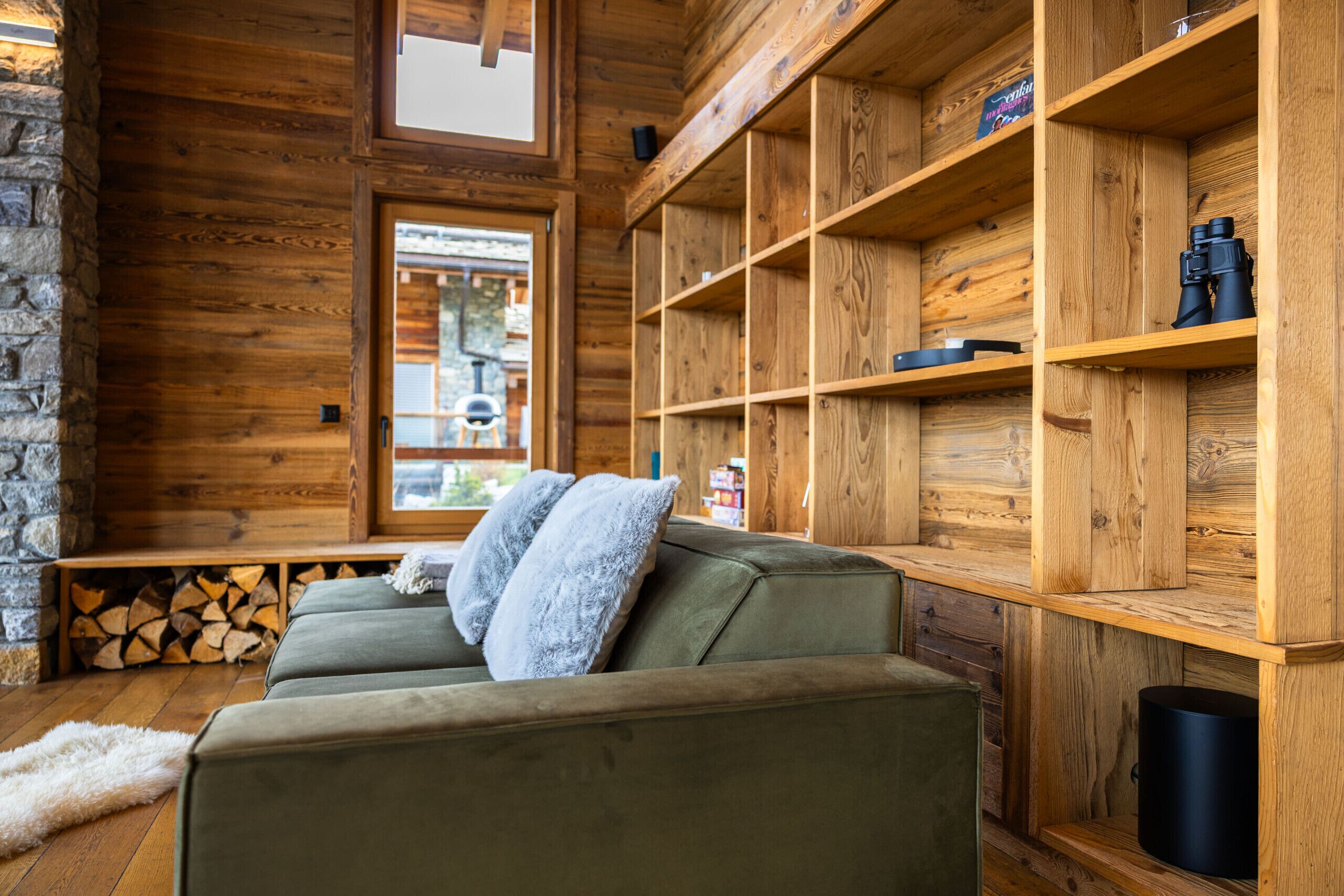 Ein gemütliches Blockhausschlafzimmer mit einem grünen Sofa, Holzregalen und einer Steinwand.