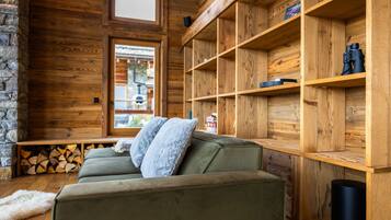 Ein gemütliches Blockhausschlafzimmer mit einem grünen Sofa, Holzregalen und einer Steinwand.