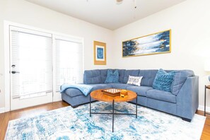 A living room with a blue sofa, a wooden coffee table, and a patterned rug. - Rebel Bluff on Depot by Apex Short Term Stays (Oxford)
