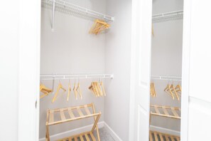 Un armario espacioso con perchas de madera y un tendedero de madera.
