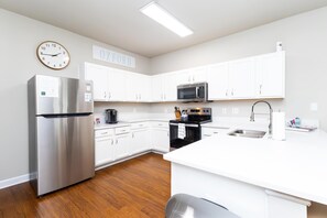 A modern kitchen with white cabinets, stainless steel appliances, and a wooden floor. - Rebel Bluff on Depot by Apex Short Term Stays (Oxford)