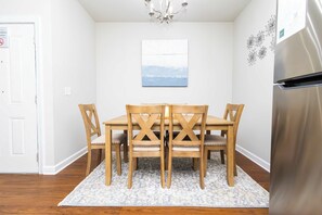 A dining area with a wooden table and chairs, a chandelier, a painting on the wall, and a refrigerator. - Rebel Bluff on Depot by Apex Short Term Stays (Oxford)