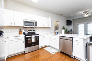 Una cocina moderna con armarios blancos, electrodomésticos de acero inoxidable y piso de madera.