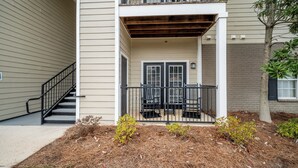 A two-story building with a covered porch, a staircase, and a small garden area. - Rebel Bluff on Depot by Apex Short Term Stays (Oxford)