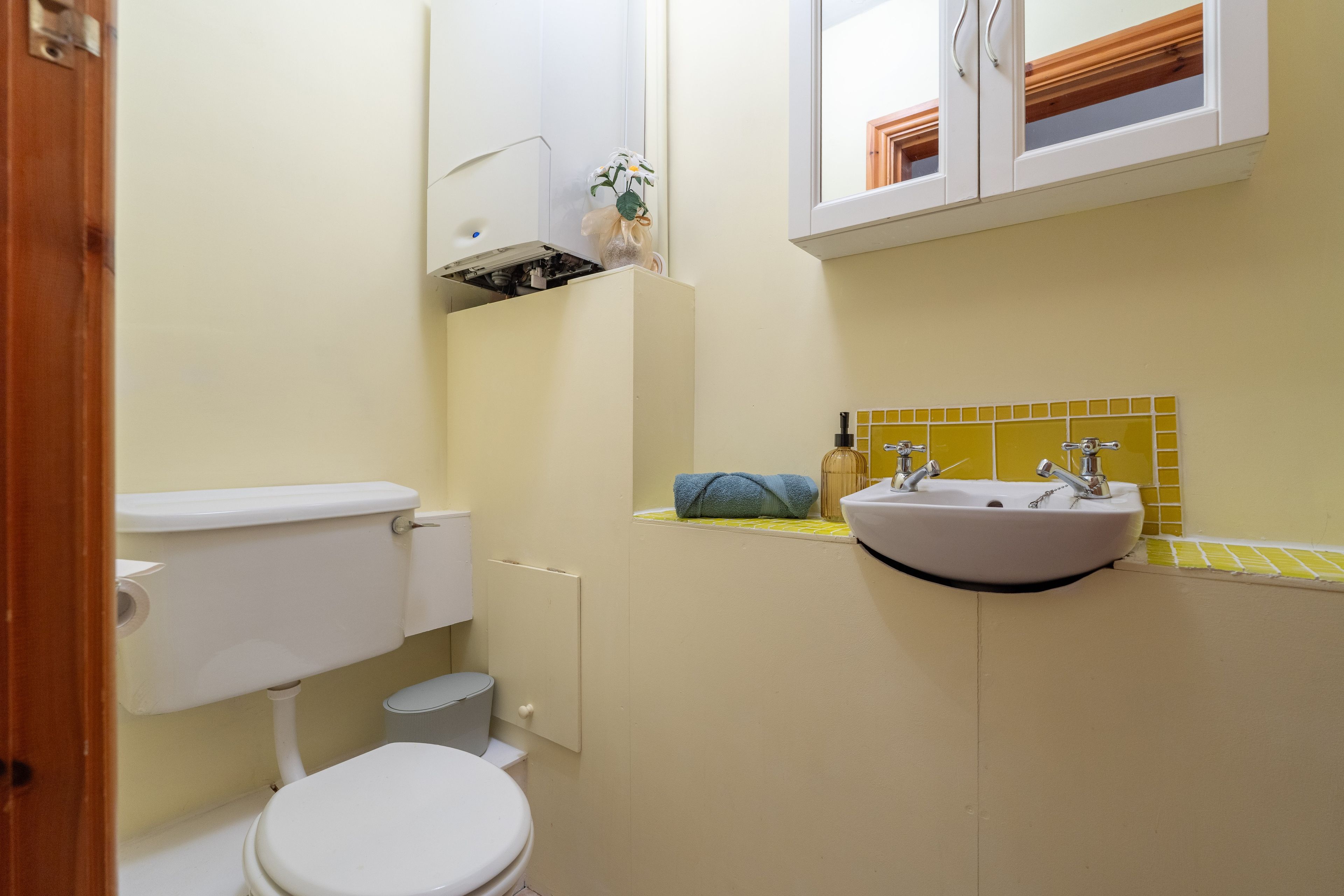 A small bathroom with a toilet, sink, and mirror.