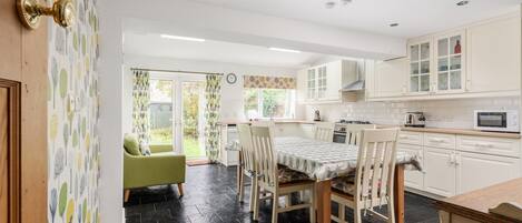 A modern kitchen with white cabinets, a dining table with chairs, and a view to the outside.
