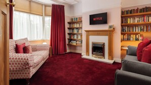 A living room with a fireplace, a bookshelf, a television, and a sofa. - Music Lovers | Piano | Pets OK & Driveway Parking (Liverpool)