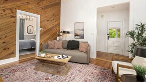 Un salon chaleureux avec un plafond en bois, un canapé gris, une table basse et un tapis à motifs.