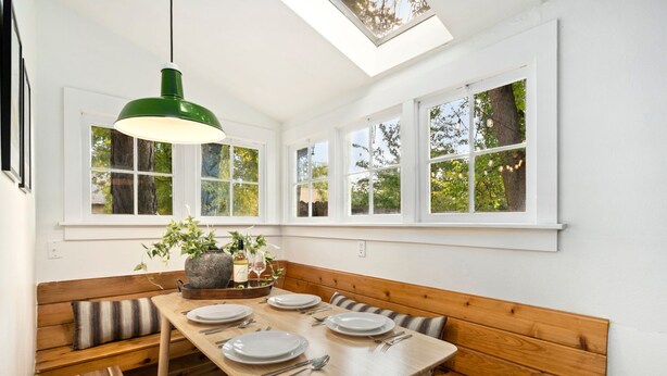 Un espace repas avec une table en bois dressée pour quatre personnes, entourée de bancs en bois.