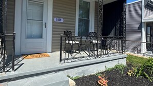 A house with a front door, a porch with a railing, a number sign '1819', and a small garden area. - La Casetta Cafe on The Hill (St. Louis)