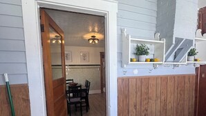 A wooden fence, a door, a dining area with chairs and a table, and a shelf with potted plants. - Casa Italiana: Cozy home in the heart of The Hill (St. Louis)