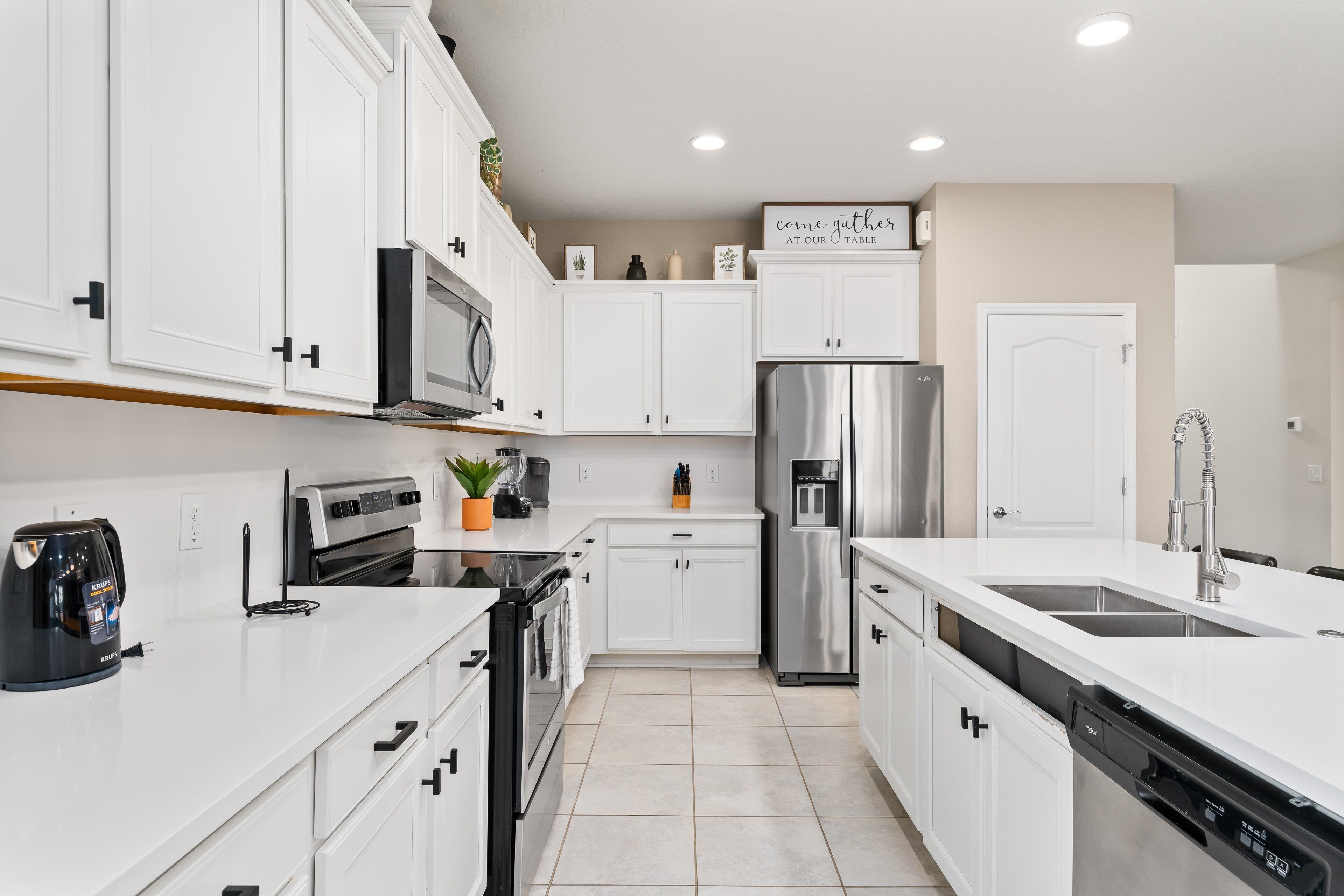 A modern kitchen with white cabinetry, stainless steel appliances, and a central island with a sink.