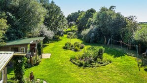A well-maintained garden with a wooden house, a circular flower bed, and a clear sky. - Apartment Nolde, 33 sqm, 1 Bedroom, Max. 2 Guests (Pellworm)